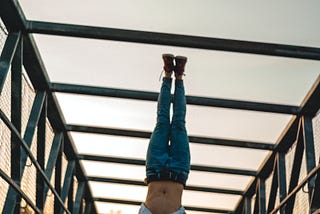 A person is holding a handstand on a bridge. Their form is good, with legs straight and feet together.