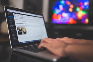 Man is writing article on WordPress on laptop.