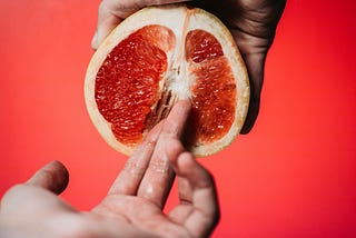 hand fingering a grapefruit cut in half