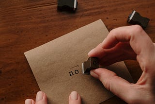 A hand stamps letter with the word no.