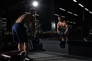 Man looking at himself in the mirror while working out