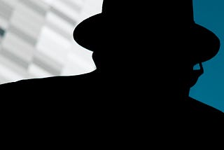 An up close, abstract street photograph of a silhouetted man wearing a hat and glasses disguising his identity.