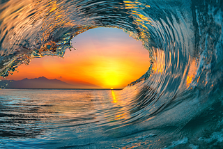 a sunset inside an ocean’s wave