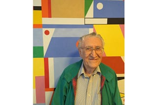 Portrait of an elderly man in a green jacket in front of a bright abstract painting.