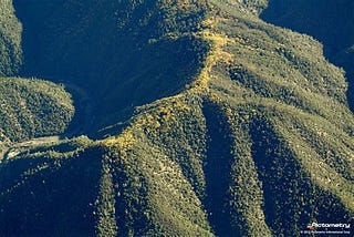 Photo of a mountain ridge. Green on both sides and brown on the ridge top path.