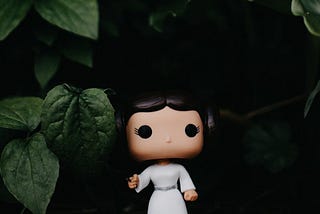 Funko Pop toy of Princess Leia in front of green leaves.