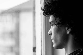 Young man looking intently out a window.