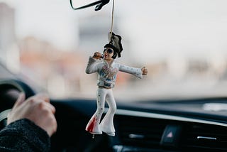 An Elvis Presley figure hanging on a rearview car mirror.