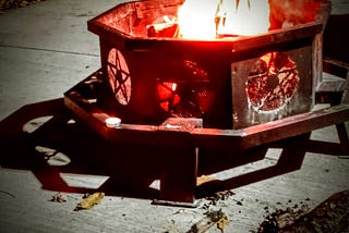 A bonfire pit lit on Halloween 2024 features a pit with a cauldron-like appeal engraved with stars. The flames honor departed loved ones.