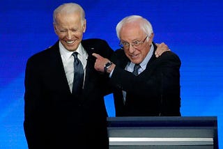 Former US vice president Joe Biden, left, embraces Sen. Bernie Sanders during a Democratic presidential primary debate