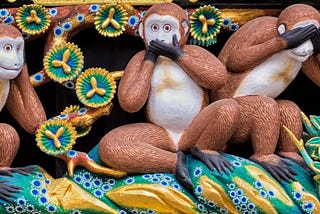 Carving of three monkeys, one covering its ears, one covering its eyes, and one covering its mouth