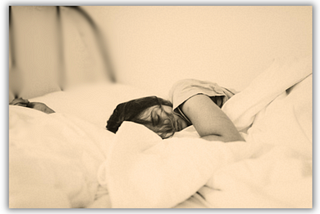A girl asleep in a white sheeted bed