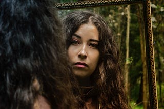Woman in a forest gazing into mirror