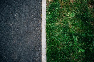 Photo of asphalt separated from grass with a white dividing line, by Will Francis on Unsplash.