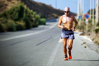 Male runner, topless, on a quiet country road.