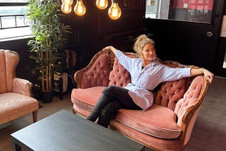 Author is sitting on a light red fabric couch in a lobby in a Thailand hotel