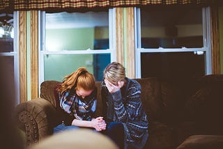 Two women crying and supporting each other