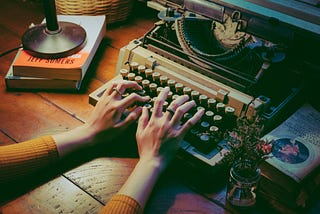 Two hands are typing on an old-looking typewriter.