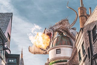 A dragon on top of a domed building breathing fire across a village