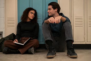 A girl (Ginny) and a boy (Marcus) sitting, on the floor, next to each other.
