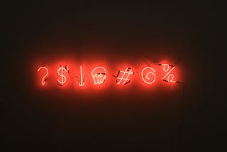 Photo of red neon text against a dark backdrop. The text is a series of seven symbols.