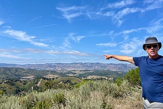 Man pointing at the mountains in teh backgroun