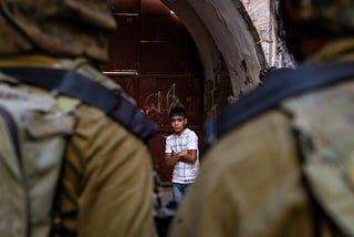 A Palestinian boy is detained by Israeli soldiers while riding his bicycle in the Old City of Hebron in the occupied West Bank, July 2015.