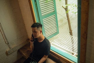 A man using his phone near a window.