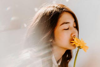 Young woman smells flowers with eyes closed, enraptured
