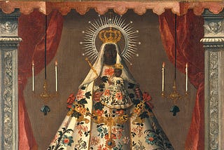 A black Madonna is positioned between two velvet red curtains as if centre stage and is dressed in beautiful, opulent robes, with a golden crown. She holds a small, identically dressed Jesus in her left arm and a golden sceptre in the right hand.