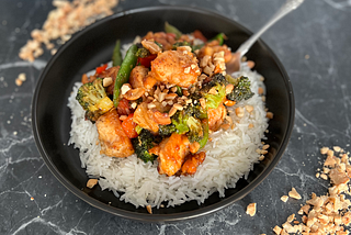 Cashew chicken stir fry on a marble surface with crushed peanuts