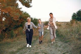 an-older-woman-with-a-younger-woman-and-a-child-running-down-a-path