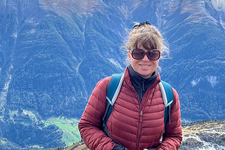 A smiling woman stands in front of the mountains