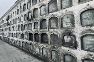 A gray wall lined with niches that hold tombs