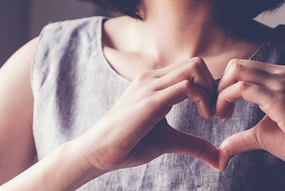 Woman holding her hands in the shape of a heart.