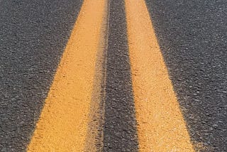 Double yellow lines running down the center of the road, into the distance