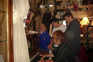 Me, two of my guy friends, and an old lady with grey hair in an antique furniture store. I’m playing the piano and everyone else is looking at me and my hands.