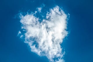 Heart-shaped white cloud against a blue sky.