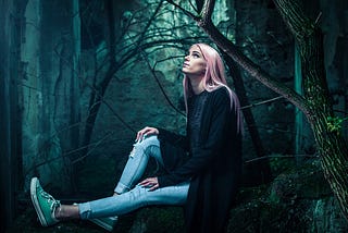 Young girl in faded denims leaning against a tree