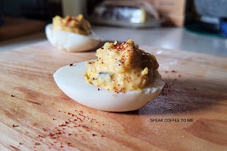 Close up of a deviled egg on a wooden cutting board