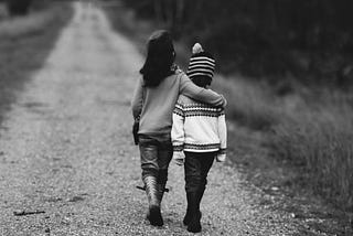 Two friends walking along a path, one with her arm around the other.