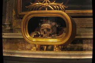 A skull is encased in a golden reliquary