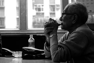 Chinese man in cafe smoking a pipe and looking out the window