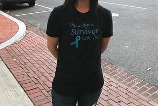 Photo of Rishika Satyarthi outside wearing “This is what a survivor looks like” t-shirt on.