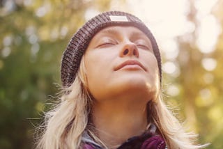 Young blonde woman with eyes closed in outdoor environment