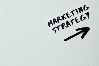 A whiteboard with “marketing strategy” and an arrow written in black ink.