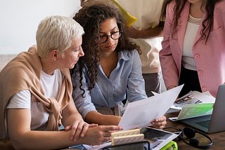A photo of two women studying a document together.