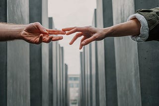 Two hands reaching towards each other against a background of buildings