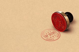 A red “top secret” stamp and stamper on a tan background