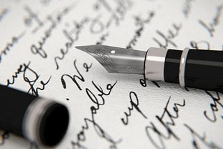 A fountain pen lies open on a page full of words written in black ink.